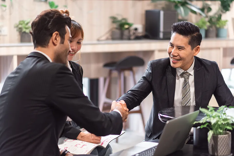 Businessmen handshake next to female secretary and laptop by partystock on Freepik