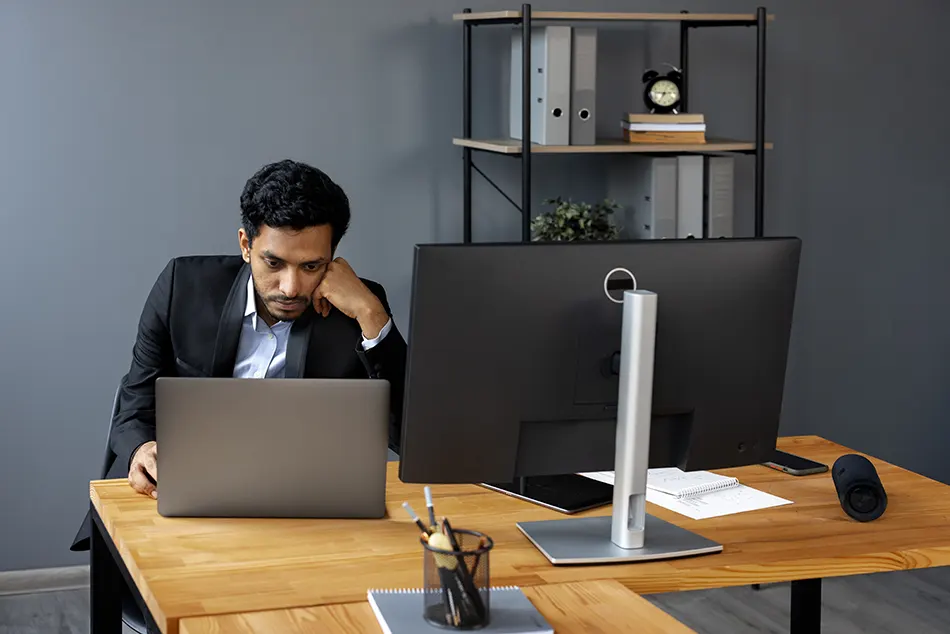 Man in business attire using laptop at office desk by Freepik